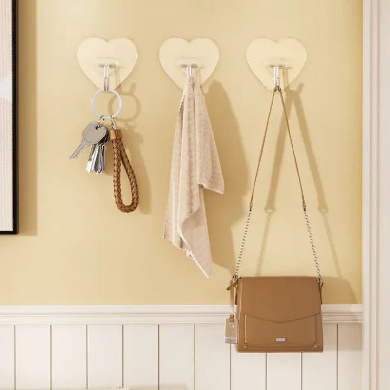A set of ten transparent self-adhesive hooks is displayed on a cream-colored wall, with a brown leather pouch hanging below.