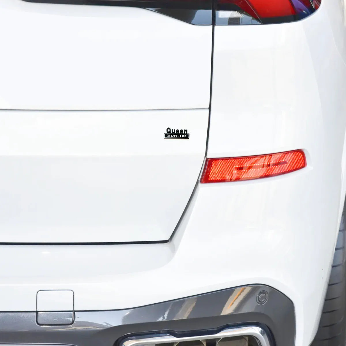 Nahaufnahme der hinteren Kotflügelseite eines weißen Autos mit dem Queen Edition Emblem und dem Rücklicht.