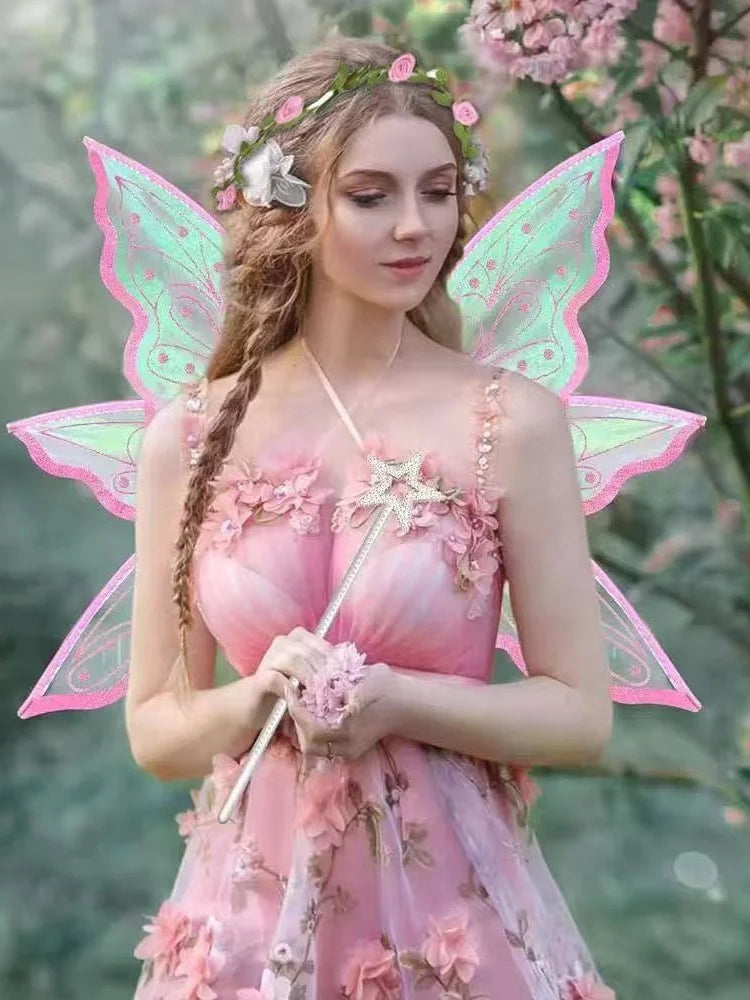 A woman wearing a pink fairy costume with butterfly wings and a flower crown, standing in a garden.