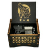 A wooden box containing a black metal music box with a gold-colored design and Japanese text.