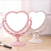 Espejos de maquillaje con forma de corazón, rosas y blancos, dobles, sobre una superficie de madera.