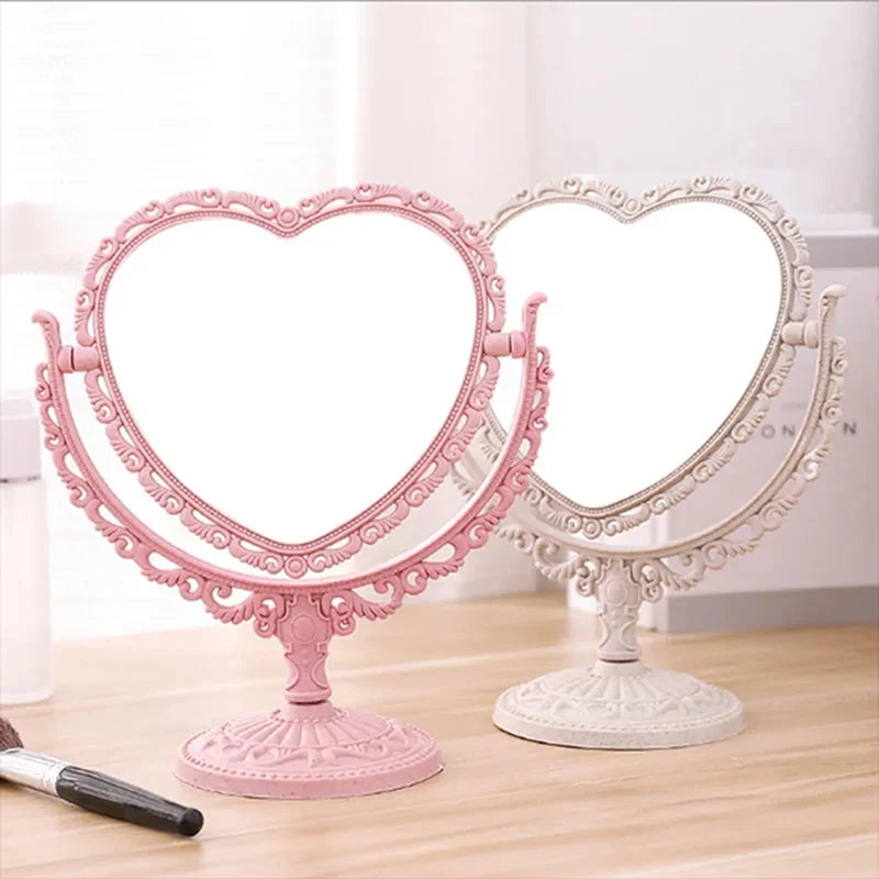 Espejos de maquillaje con forma de corazón, rosas y blancos, dobles, sobre una superficie de madera.