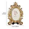 Vintage gold oval resin picture frame with ornate detailing and a white background