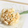 A bouquet of light yellow silk peonies with green stems arranged on a white surface.
