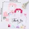 Pink floral thank you gift bags with pink ribbon handles displayed on a white background.