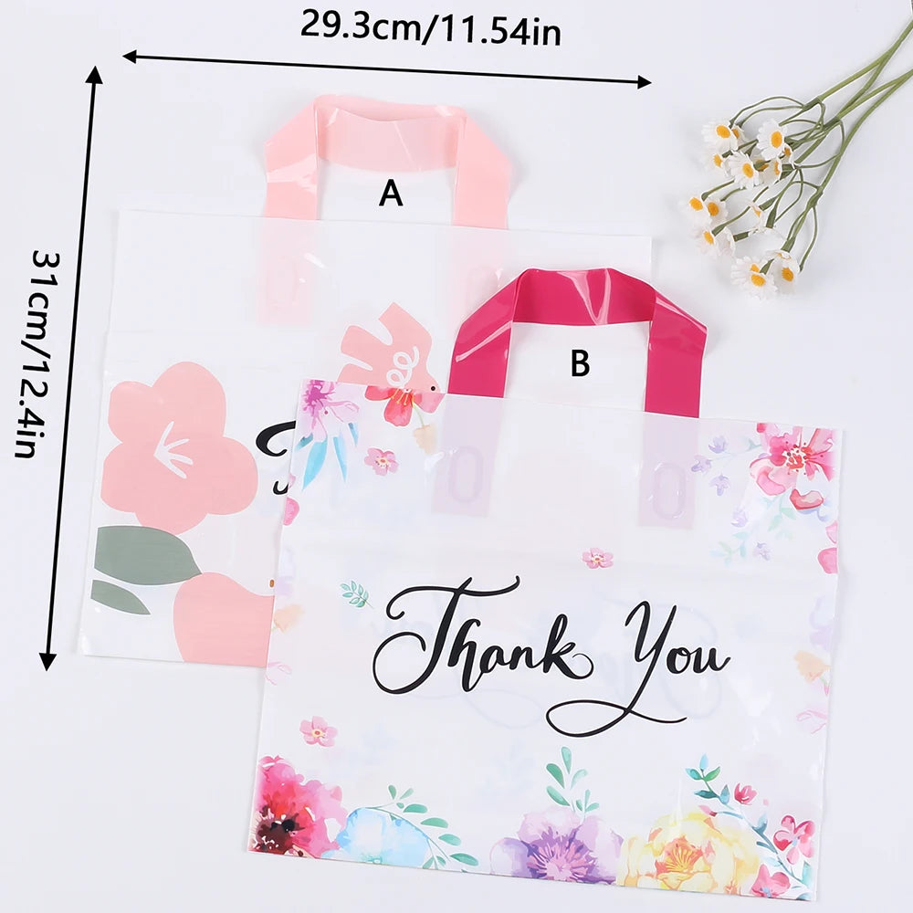 Pink floral thank you gift bags with pink ribbon handles displayed on a white background.