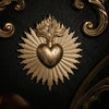 Gold relief plaque depicting a sacred heart surrounded by radiating rays on a dark background.