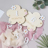 Wooden monthly milestone cards featuring large cloud shapes with numbers and text on pink fabric