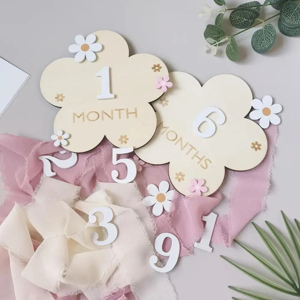 Wooden monthly milestone cards featuring large cloud shapes with numbers and text on pink fabric