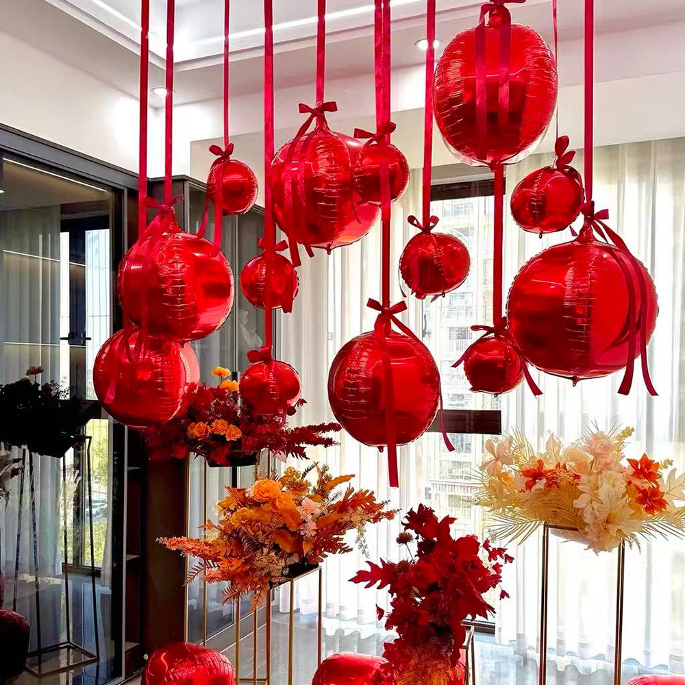 A collection of glossy red round foil balloons are suspended in a vertical display.