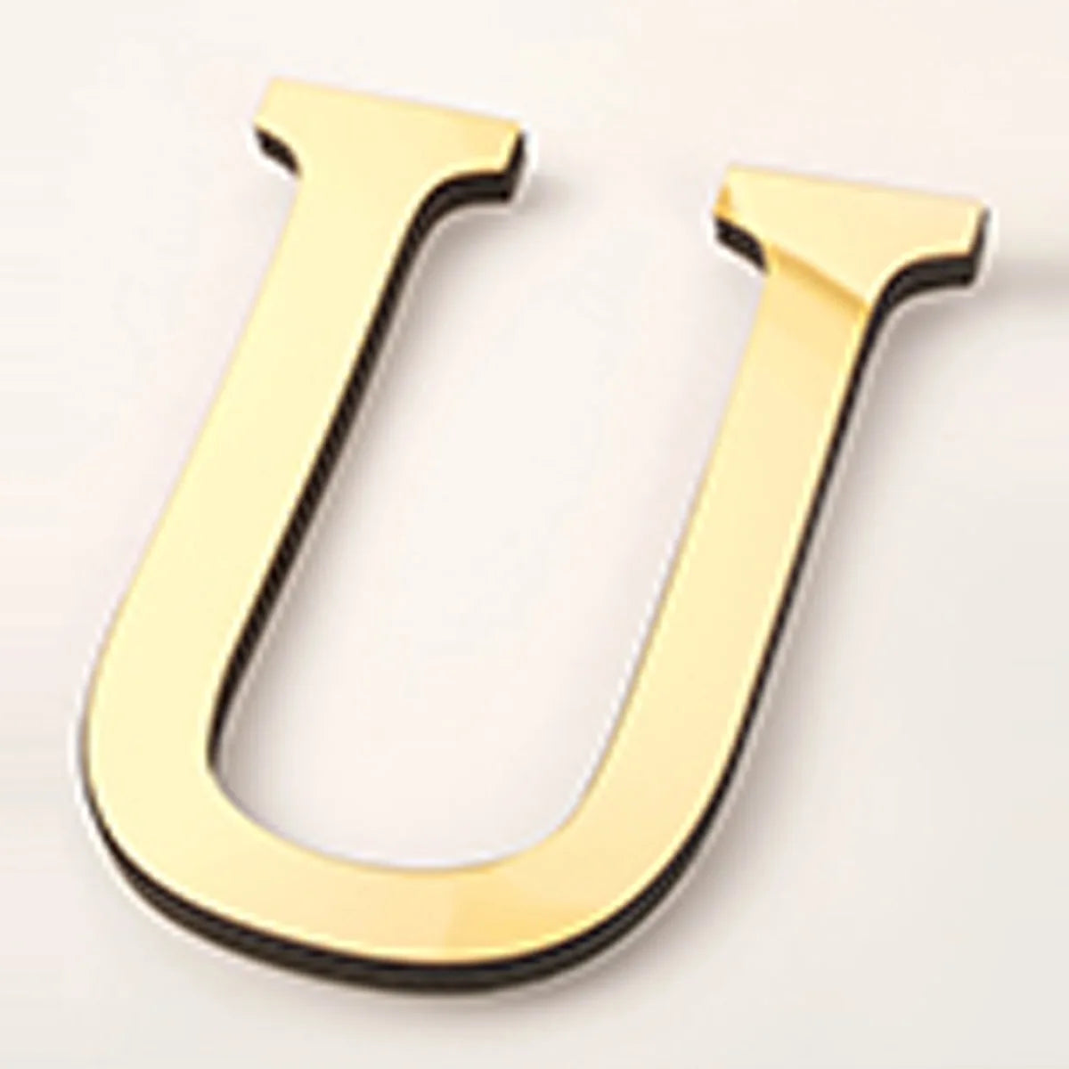 A gold acrylic mirror letter U wall sticker with a black edge.