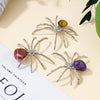 Three handcrafted crystal spider figurines with various colored bodies displayed on a light background.