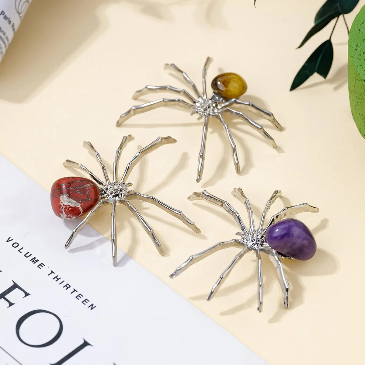 Three handcrafted crystal spider figurines with various colored bodies displayed on a light background.
