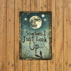 A vintage metal wall decor piece featuring a moon and dragonfly quote on a distressed plaque.