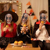 Three young women wearing creepy clown masks and costumes posing indoors.