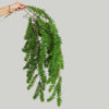 A hand is holding a long, green artificial hanging ivy vine with small leaves.