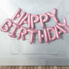 A pink foil letter balloon banner spelling out Happy Birthday decoration set.
