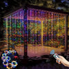 A display of vertical fairy lights creating a shimmering curtain effect in an outdoor setting.