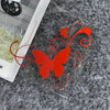 Red vinyl butterfly sticker with swirling lines placed on a gray textured surface.
