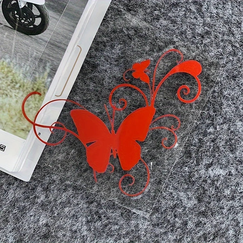 Red vinyl butterfly sticker with swirling lines placed on a gray textured surface.
