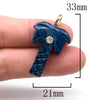 A hand holds a deep blue natural crystal pendulum with a zircon charm, showing its size and detail.