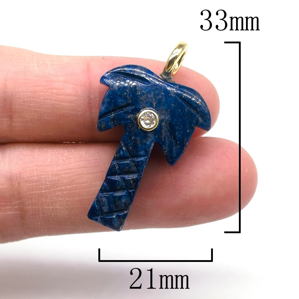 A hand holds a deep blue natural crystal pendulum with a zircon charm, showing its size and detail.