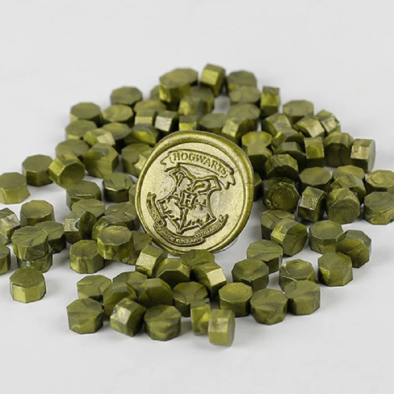 A pile of small, olive green wax sealing beads shaped like tiny cubes.
