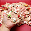 A hand holds a pile of assorted Christmas resin fridge magnets featuring Santa, snowmen, and tree designs.
