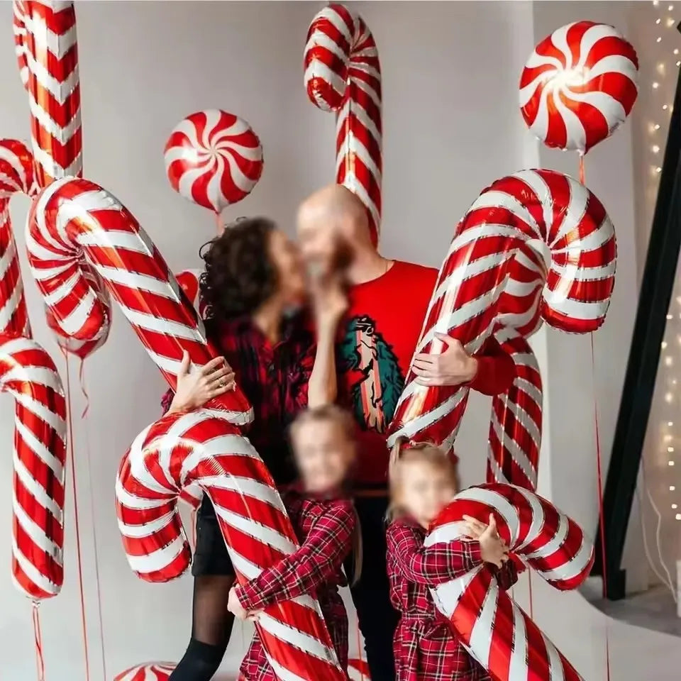 A group of people are holding red and white candy cane foil balloons for Christmas party decor.