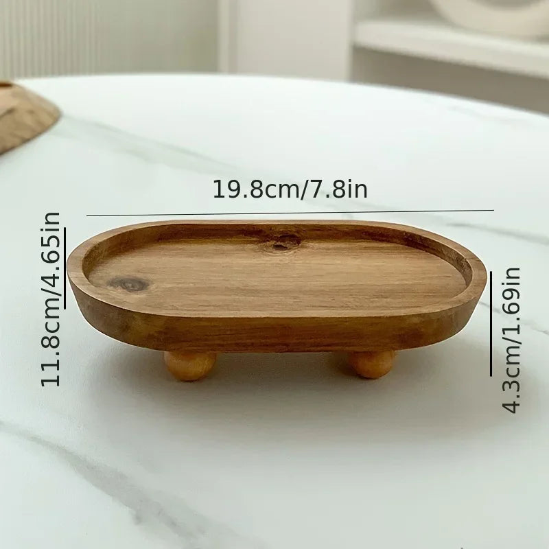 A light brown elliptical wooden storage tray with small feet, shown on a white marble surface.