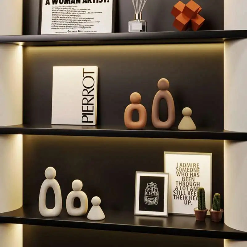 A display of modern resin family statues in various skin tones on dark shelves.