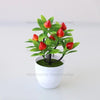 Artificial lemon tree bonsai with bright red fruit growing in a white pot