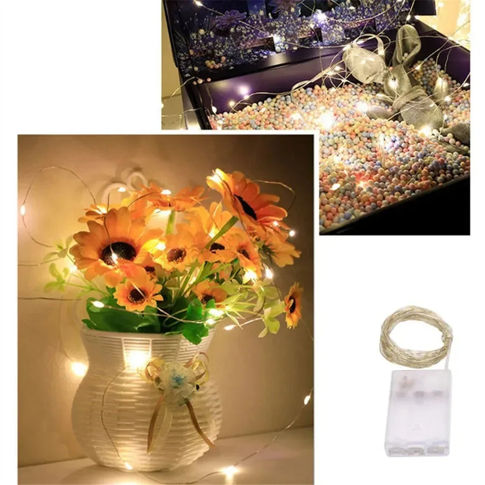 A white woven vase holds bright orange flowers illuminated by fairy string lights.