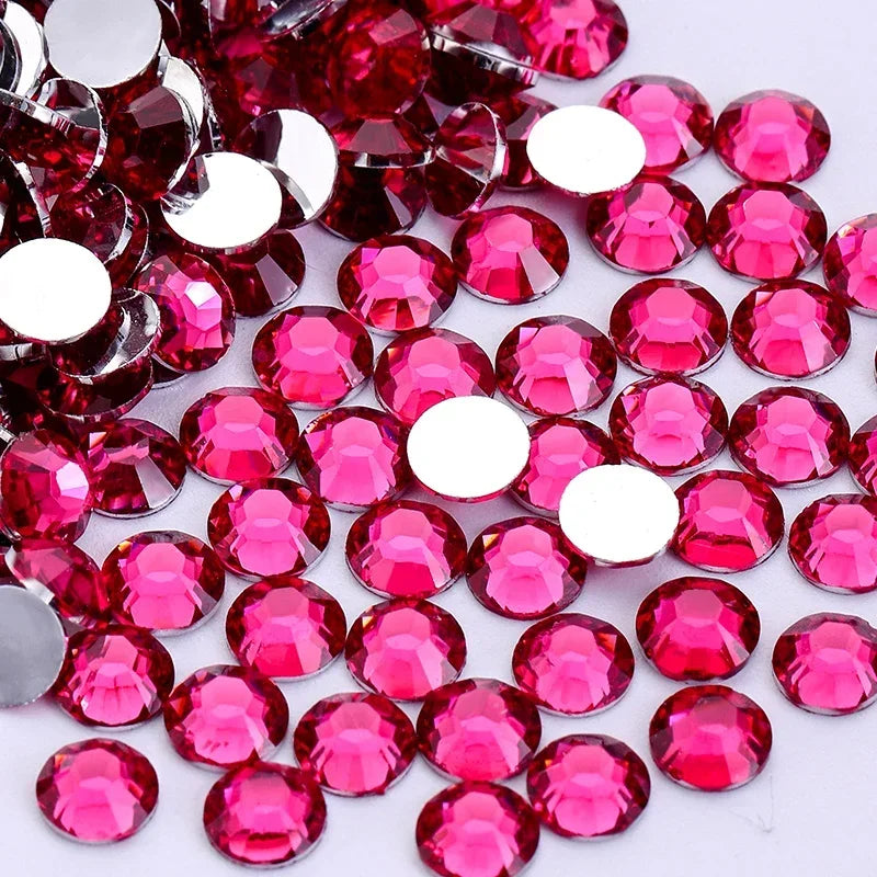 A close-up view of round flatback resin rhinestones in various shades of pink and red.