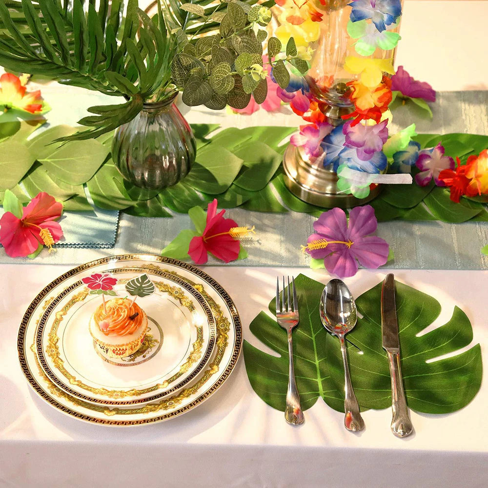 Artificial tropical palm leaves used as party decor surrounding a plate of food and floral arrangements.