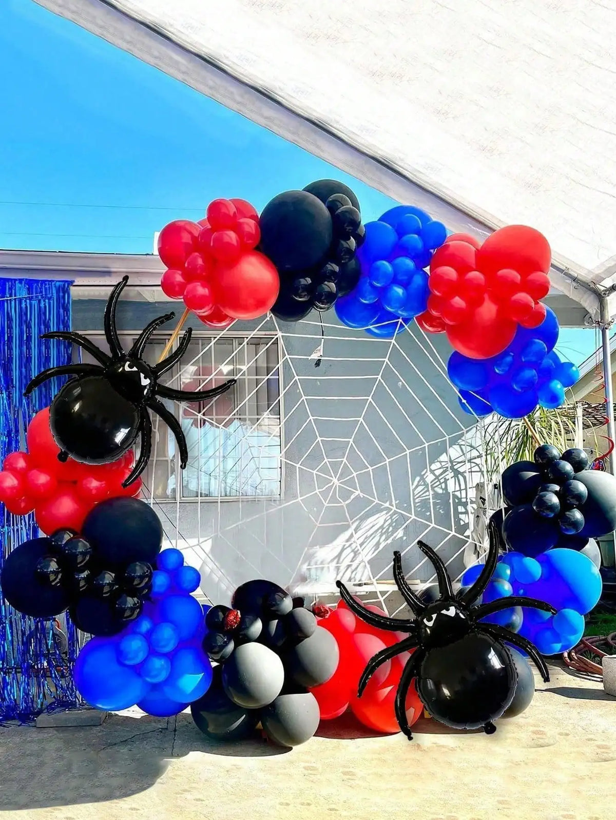 Une arche de ballons avec des ballons noirs, rouges et bleus en forme d'araignées et autres sphériques.