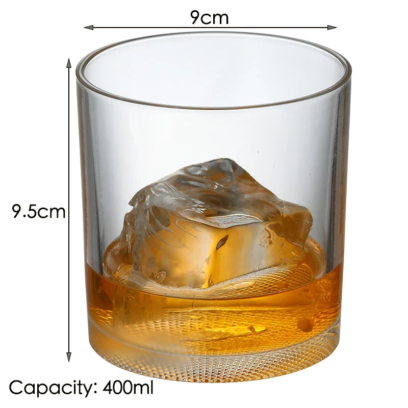 A clear glass tumbler filled with amber whiskey and a large ice cube.