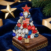 A detailed rhinestone Christmas tree brooch pin with red, blue, and clear stones rests on a wooden box.