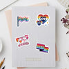 A sheet of graph paper features various colorful pride and love themed stickers including a pride flag, heart shapes, and LGB