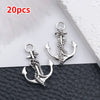 20 pieces of vintage ship anchor charms for jewelry making displayed on a black leather surface