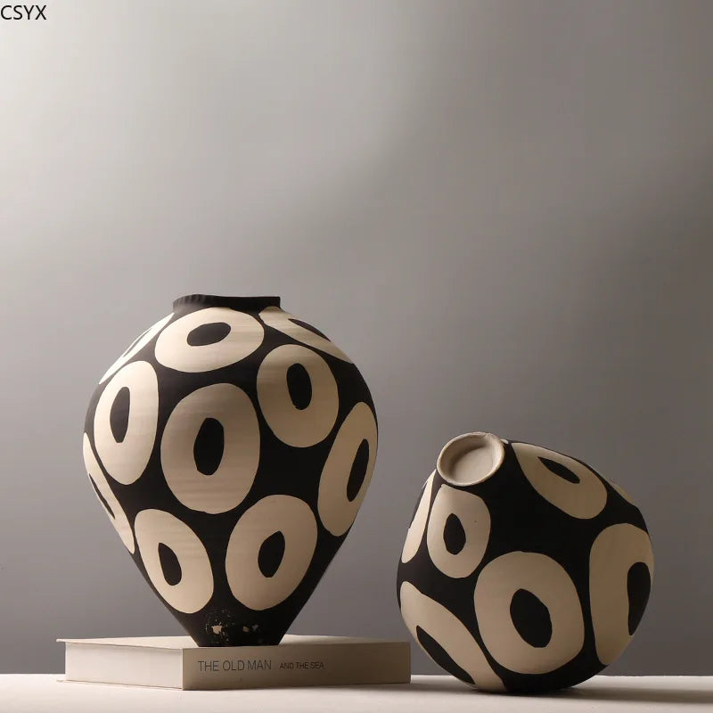 A black and beige ceramic vase with a geometric circle pattern displayed on a light surface.