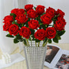 A bouquet of vibrant red artificial roses in a white textured planter