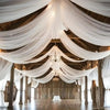 Elegant white sheer chiffon curtains draped across a wooden ceiling in an event venue.