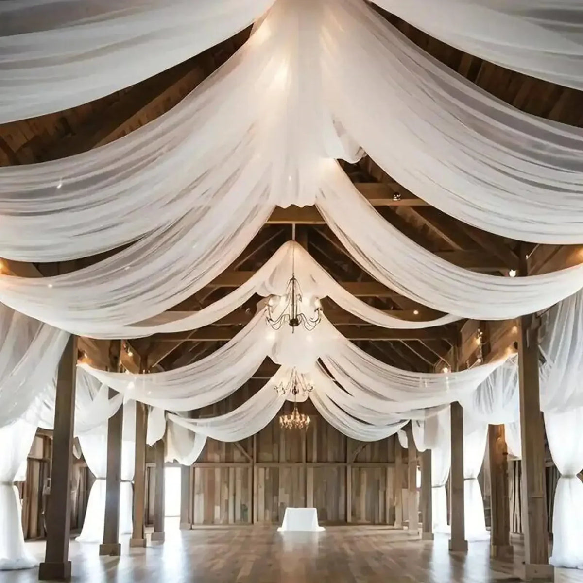 Elegant white sheer chiffon curtains draped across a wooden ceiling in an event venue.