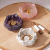 A set of natural crystal droppers in pink and purple glass are displayed on a wooden surface.