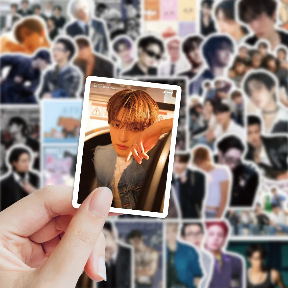 A hand holds a photo of a K-Pop idol, likely used as a sticker or accessory for luggage.
